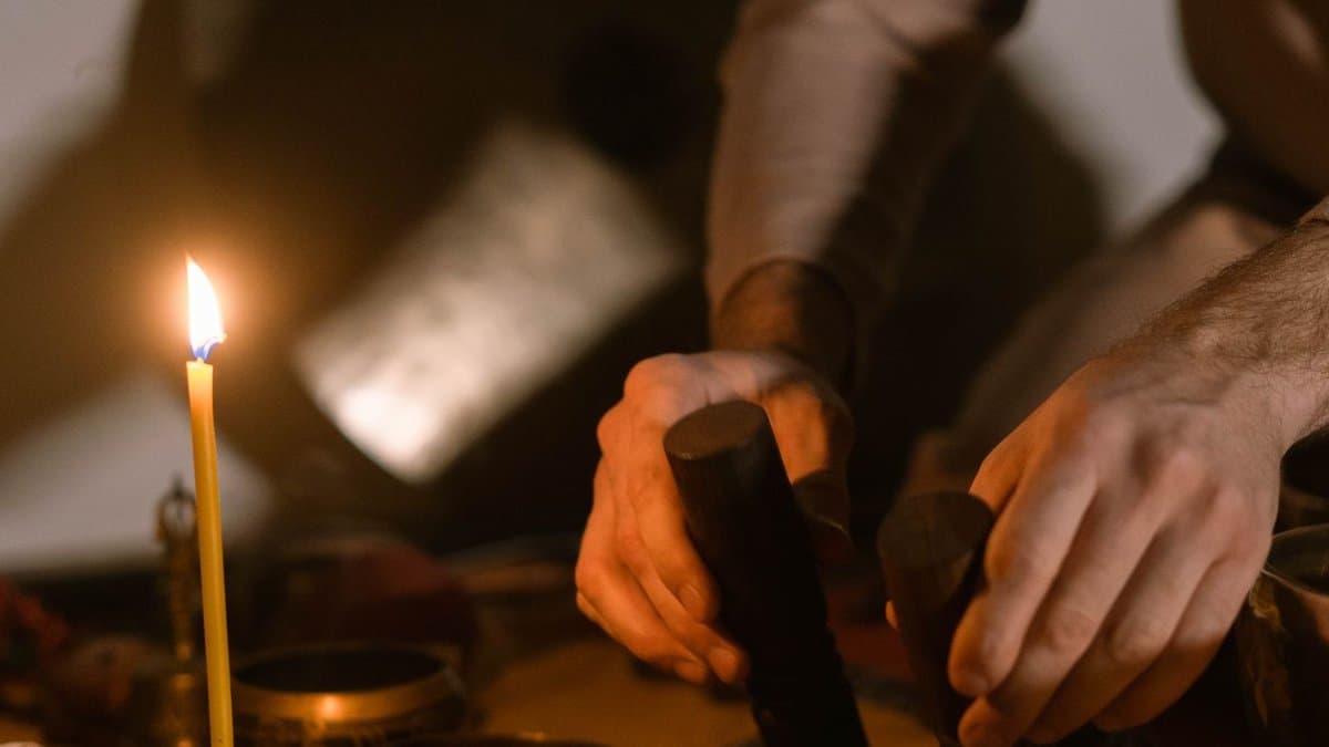 Bols chantants et maillet posés près d'une bougie allumée, dans une pièce sombre