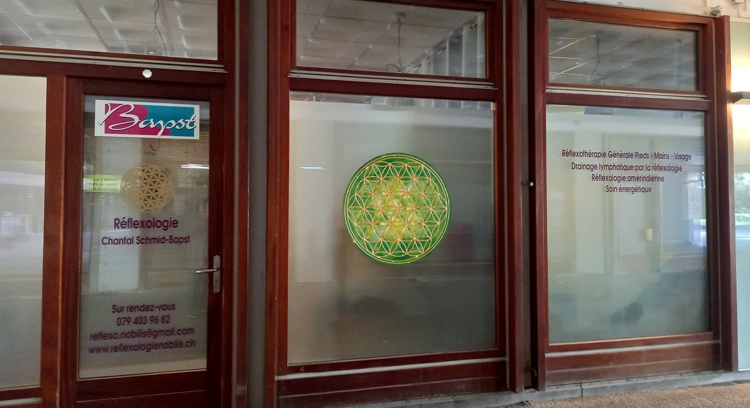La devanture du cabinet, Cité Vieusseux 9D à Genève : la porte au nom de Chantal Schmid-Bapst et la Fleur de Vie collée sur la vitrine