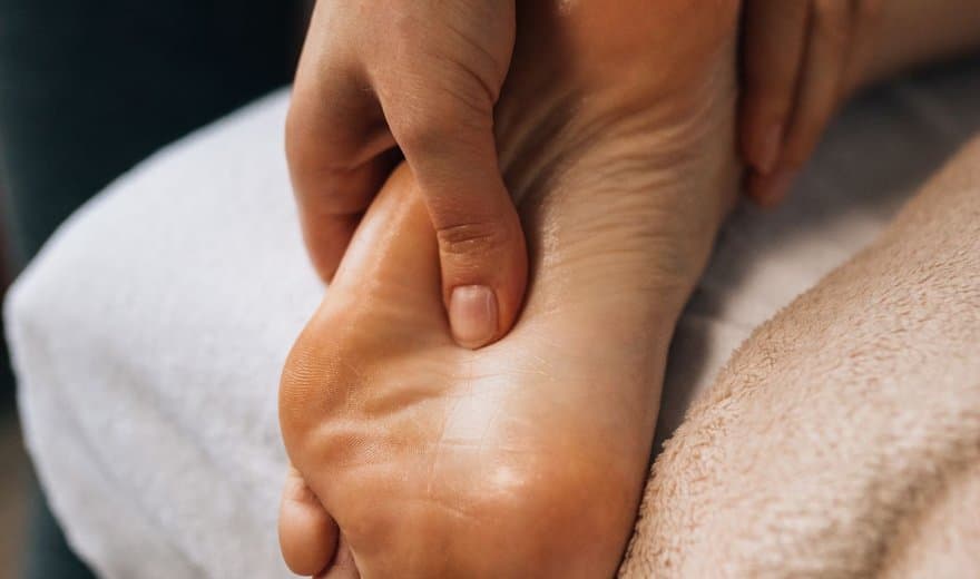 Pression du pouce sur la voûte plantaire, pied posé sur un linge